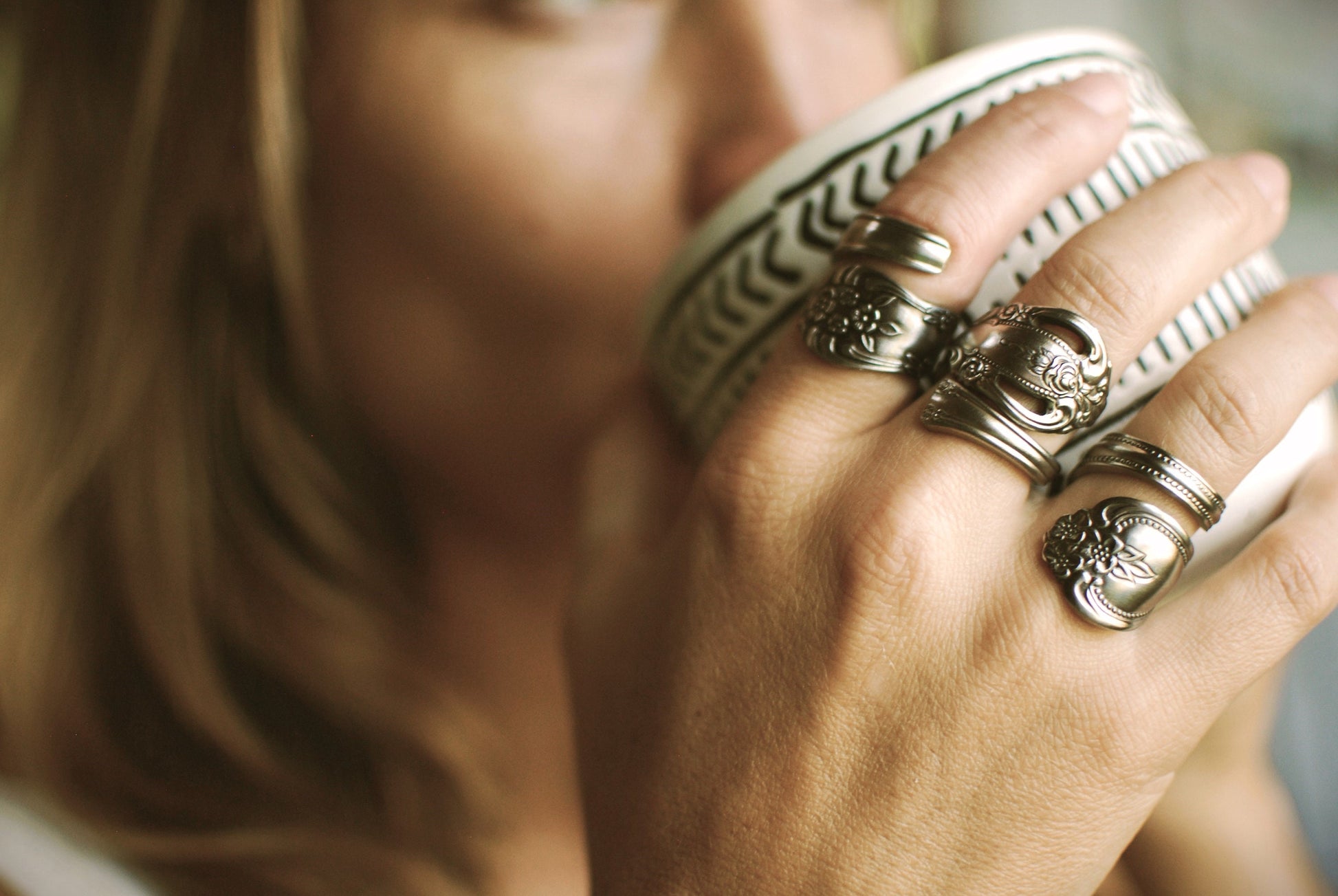 May include: Four silver rings with ornate designs. The rings are worn on the fingers of a hand.