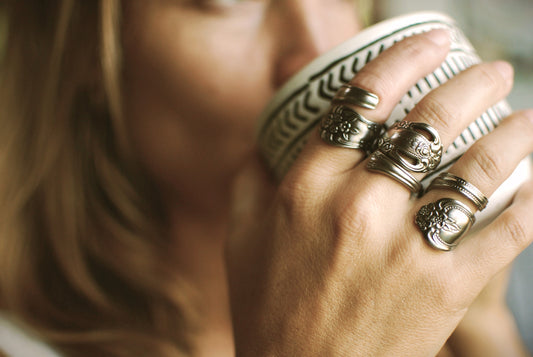May include: Four silver rings with ornate designs. The rings are worn on the fingers of a hand.
